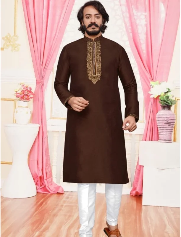 Man dressed in a brown Kurta for men with intricate golden embroidery, standing gracefully in a beautifully decorated indoor setting.